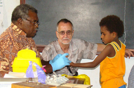 Sir Richard Feachem of Malaria Reference Group looks on as staff take a girls blood slide
