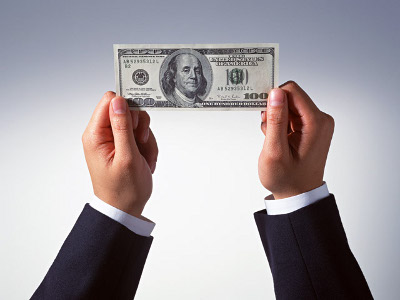 Hands holding up a 100-dollar bill